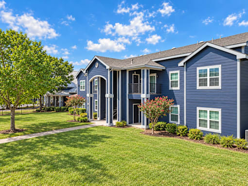 A blue house with a white fence and a green lawn.
