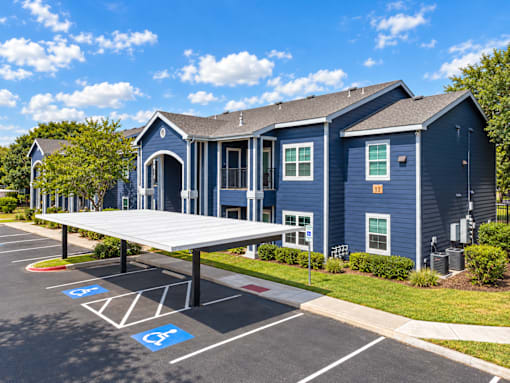 A parking lot with a blue building and a covered parking area.