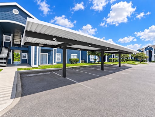 A parking lot with a blue building and a white canopy.