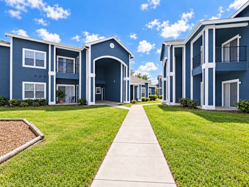 A row of blue apartment buildings with a walkway in the foreground.