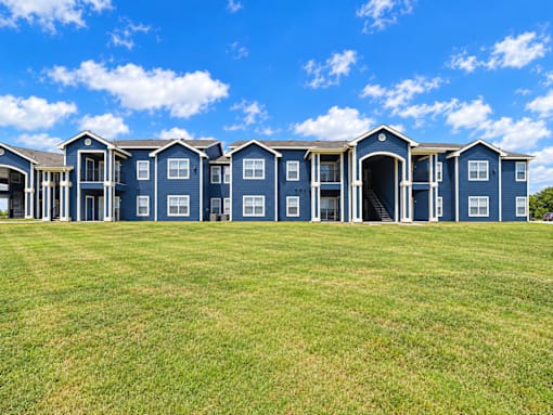 A row of blue houses with green lawns in front.