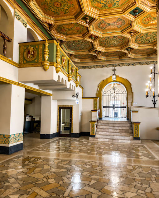 A grand staircase with a golden railing leads to a doorway.