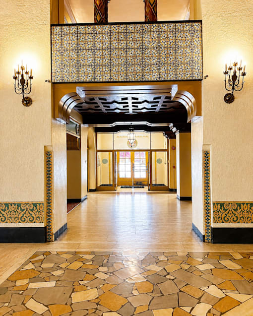 A hallway with a patterned floor and a chandelier hanging from the ceiling.