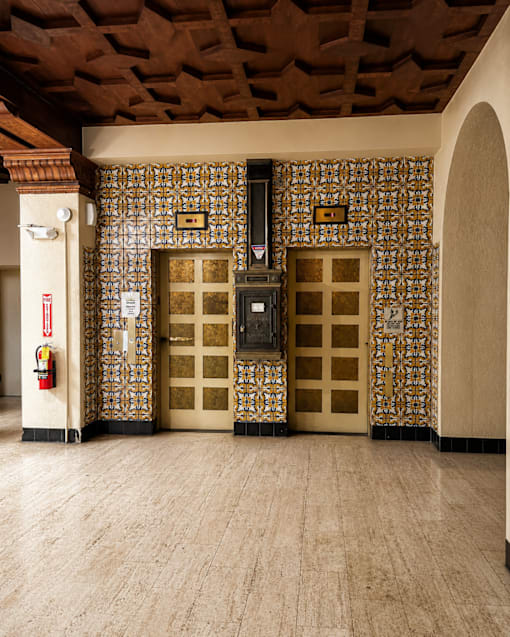 A room with a wooden ceiling and a wall with a patterned tile design.