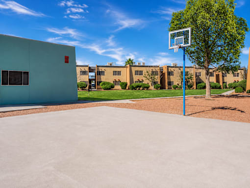 A basketball court with a hoop and a building in the background.