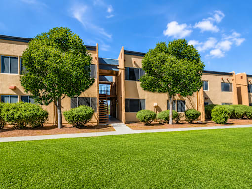 A building with a green lawn in front and trees around it.