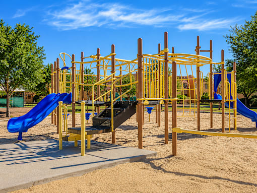 A playground with a yellow structure and a blue slide.