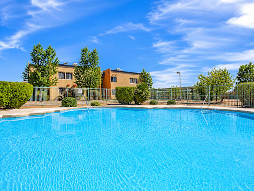 A swimming pool in front of a building with a fence around it.