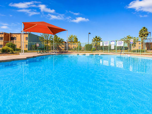 A large swimming pool with a red umbrella.