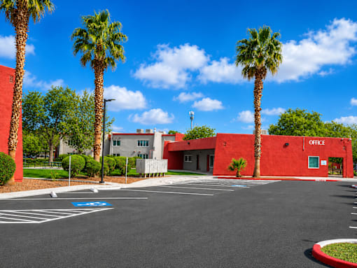 A red building with palm trees in front of it.