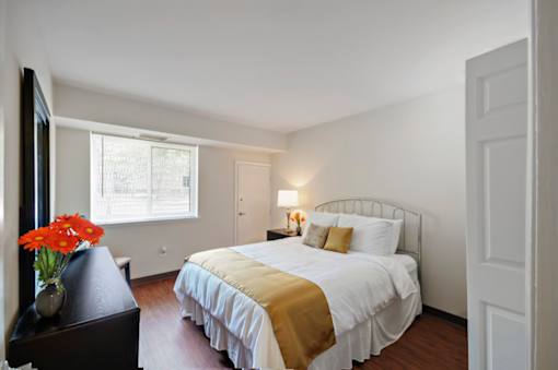 A bedroom with a bed, nightstand, and window.