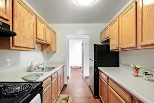 A kitchen with wooden cabinets and a black refrigerator.