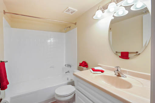 A white bathroom with a toilet, sink, and mirror.