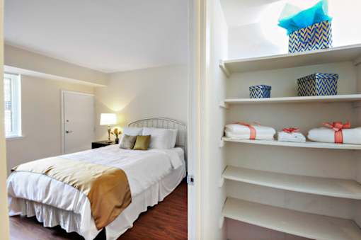 A bedroom with a bed and a closet with shelves.