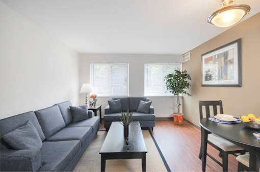 A living room with a grey couch, a black coffee table, and a dining table with chairs.
