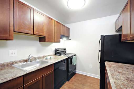 A kitchen with brown cabinets and a black fridge.