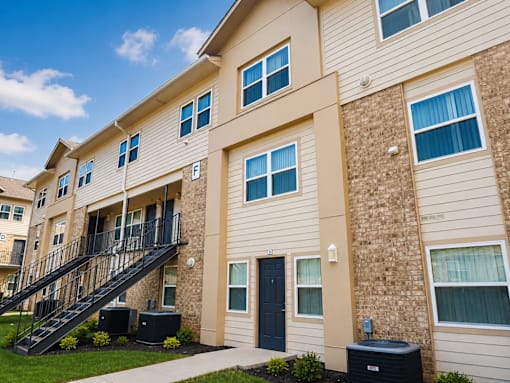 A beige apartment building with a black door and a black staircase.
