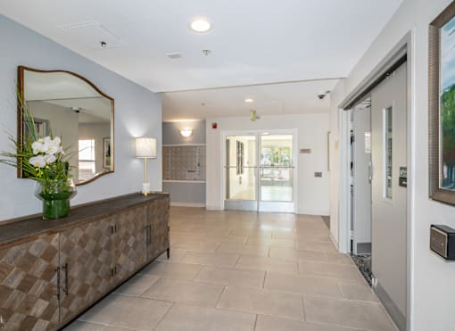 A hallway with a brown checkered bench and a mirror above it.
