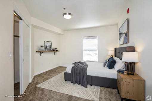A bedroom with a bed, nightstand, and a window.