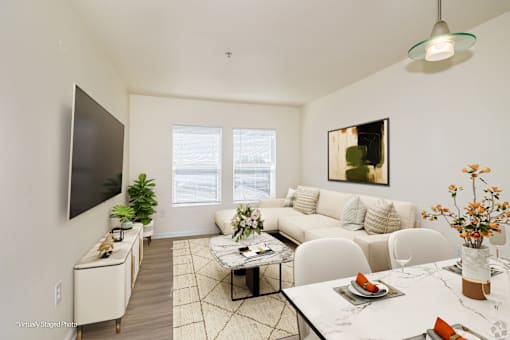 A living room with a white couch, a coffee table, and a television.