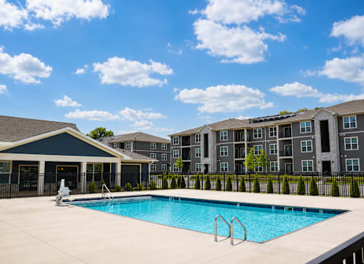 A swimming pool in front of a building with a black fence.