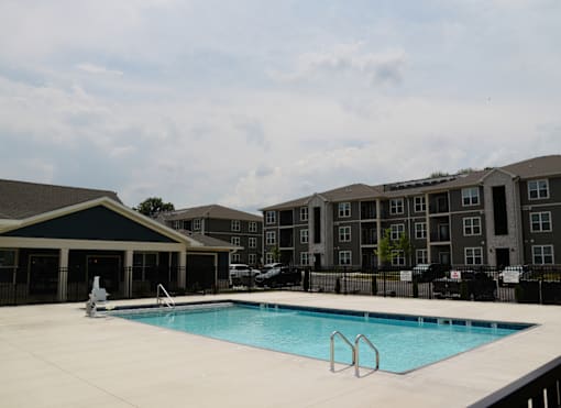A swimming pool in front of a building with a black fence.