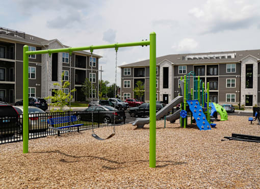 A playground with a green swing set and a blue slide.