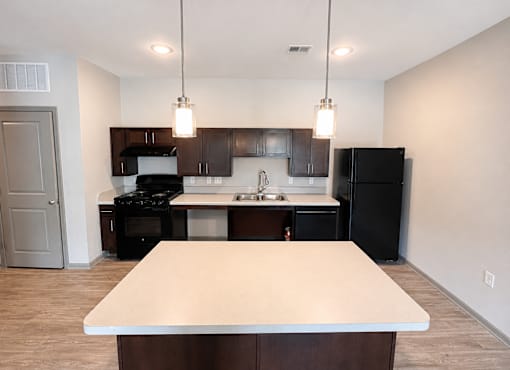 A kitchen with a black refrigerator and a white island.