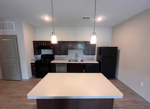 A kitchen with a table in the foreground and a refrigerator, sink, and cabinets in the background.