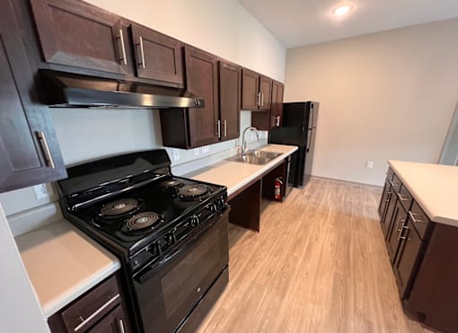 A kitchen with a black stove top oven and wooden cabinets.