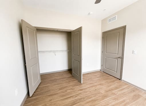 A room with a wooden floor and two doors, one of which is open.