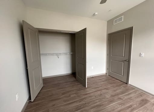 A room with a wooden floor and two open doors.