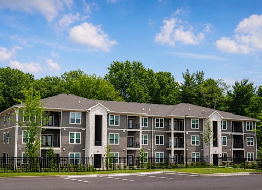 A large apartment building with a black fence in front.