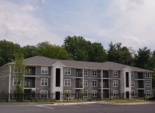 A large apartment complex with a black fence in front.