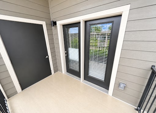 A black door is on the left and a window with blinds is on the right.