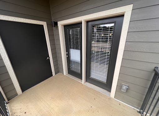 A black door is on the left and a window with blinds is on the right.