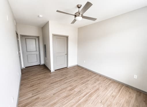 A room with a ceiling fan and two doors.