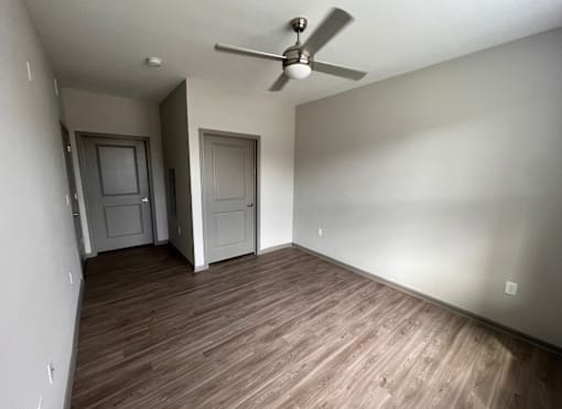 A room with a ceiling fan and wooden flooring.