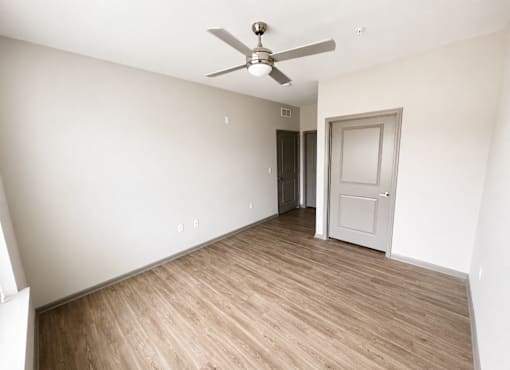 A room with a ceiling fan and wooden flooring.