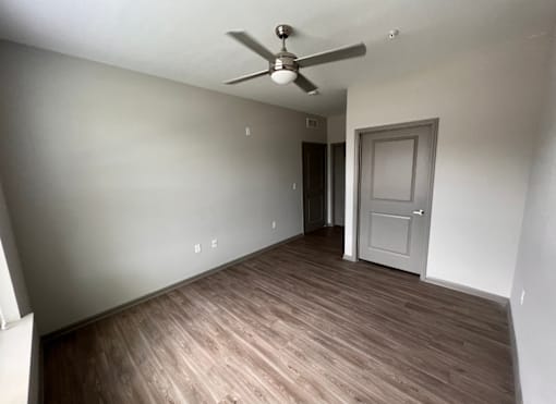 A room with a ceiling fan and wooden flooring.