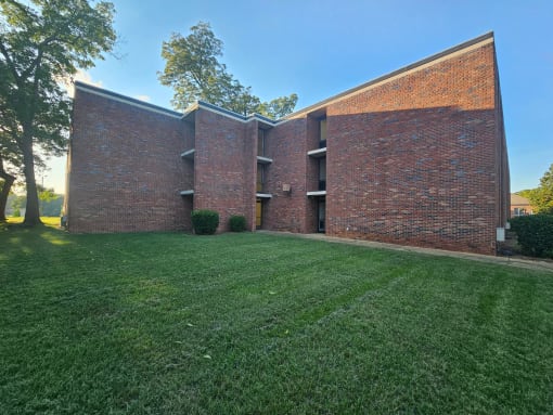 the side of a brick building with green grass