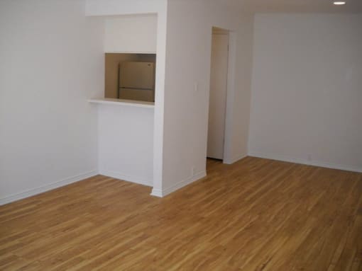 an empty room with a white wall and wooden floors
