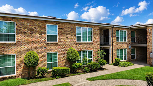 A brick building with green bushes in front.