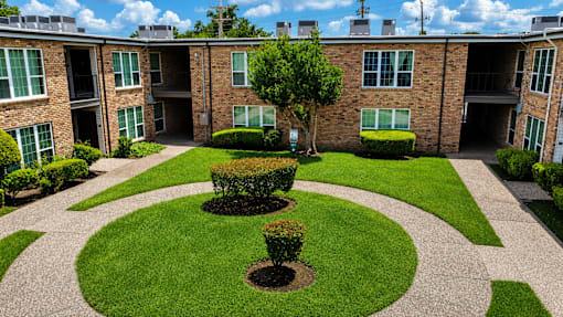 A courtyard with a tree and bushes in the middle of a brick building.