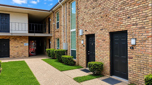 A brick building with a balcony and black doors.