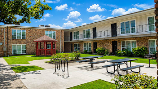 A sunny day at the courtyard of a brick building with a red entrance and a gazebo.