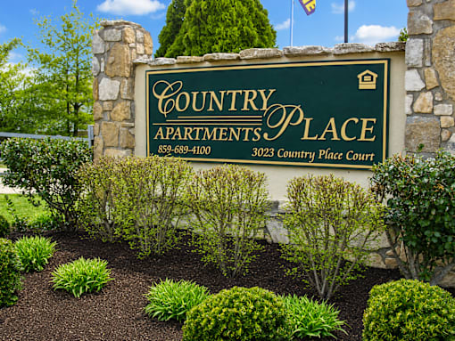 A sign for Country Apartments Place with a phone number and address.