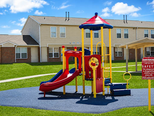 A playground with a red and yellow slide and a blue and red top.