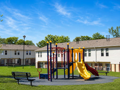 A playground with a yellow slide and a red and blue structure.