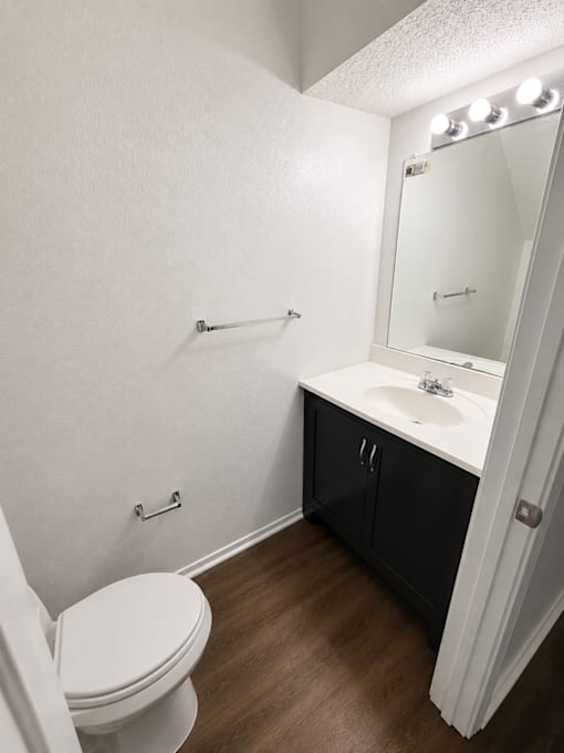 A white toilet sits in a bathroom with a sink and mirror.